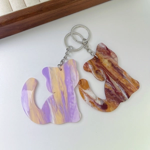 Cat-shaped acrylic keychains with colorful marble texture and metal rings on a tray