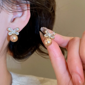Macro detail of elegant champagne gold pearl earrings with sparkling bowknot zircon crystals