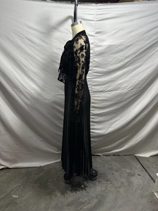 Detail of sheer lace bodice with floral flocking and pleated skirt on a black maxi dress
