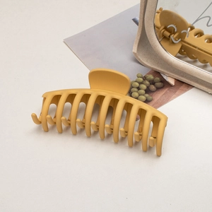 Close-up of a large matte ginger yellow shark hair claw clip on a minimalist background