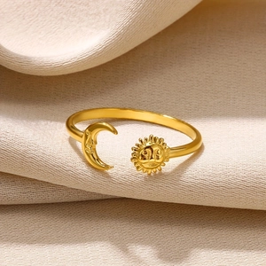 Golden stainless steel sun and moon open ring displayed on soft beige fabric