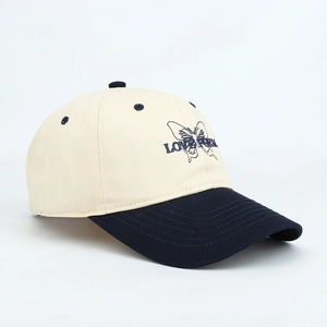 Detailed view of a beige and navy baseball cap featuring butterfly embroidery and text.