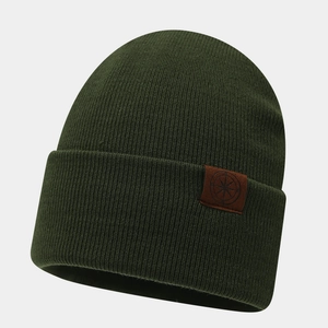 Close-up of dark green ribbed knit beanie featuring a brown leather compass patch