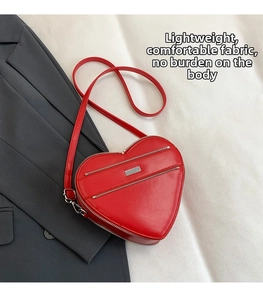 Detail showing red heart-shaped leather bag with decorative zippers on a stylish suit