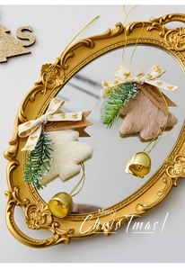 Detail of plush Christmas tree ornaments with gold bells on a vintage mirror