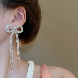 Close-up of sparkling bow-knot tassel earrings on model showing diamond fringe detail
