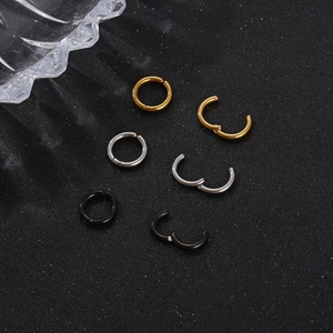 Trois paires de créoles en acier inoxydable en or, argent et noir sur fond sombre