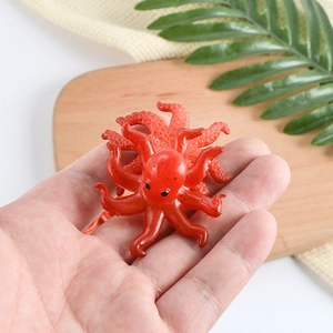 Realistic PVC mini red octopus keychain accessory displayed on a person's palm for size
