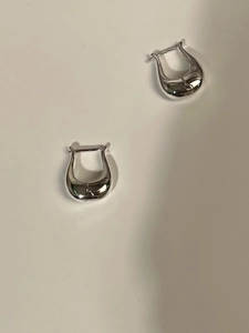 Close-up of minimalist silver tulip U-shaped stud earrings in a polished metallic finish