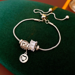 Macro detail of silver charm bracelet with heart patterns and zircon on green velvet