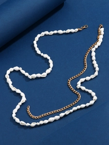 Detailed view of bohemian beach body chain with white shells and gold metal lobster clasp