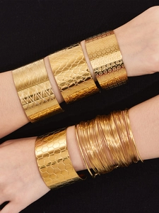 Détail de bracelets manchettes texturés en acier plaqué or 18k portés par un mannequin