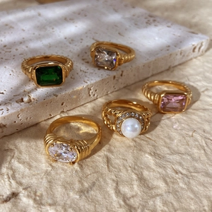 Makroaufnahme von 18K vergoldeten Ringen mit Smaragd-, Zirkon- und Perlendetails