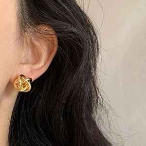Minimalist golden metal twisted knot stud earrings for women shown on ear