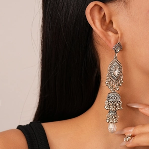 Macro side view of silver vintage tassel earrings with crystals and bell detail