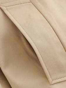 Macro shot of precise stitching on pockets of the khaki short trench coat fabric