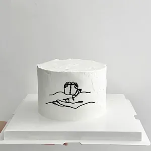 Detail of minimalist black line art on cake showing hands holding baby feet decoration
