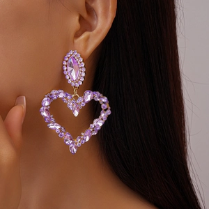 Macro detail of oversized purple heart drop earrings with glittering crystals