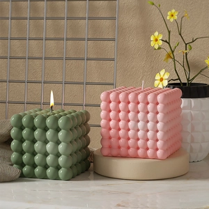 Dettaglio delle candele profumate a cubo di bolle in verde salvia e rosa tenue per casa