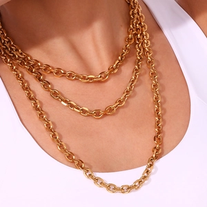 Close-up of gold layered chain necklace with bold oval links on a model's neck