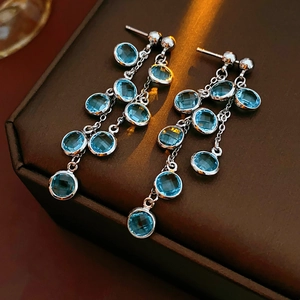 Detailed close-up of teardrop earrings with blue gemstones and dangling silver chains