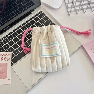 Off-white quilted cotton drawstring storage bag with pink cord and brand label