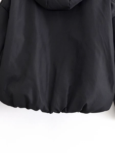 Detail view of the black puffer jacket showing smooth fabric texture and elastic hemline