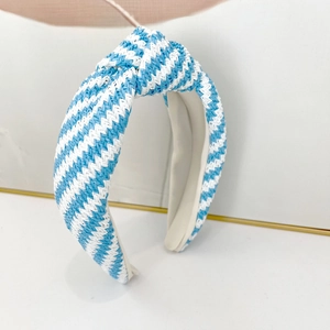 Détail d'un serre-tête tressé à rayures bleues et blanches avec un nœud et texture tissée