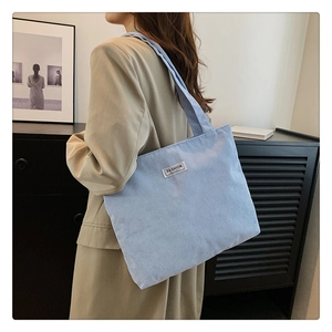 Detail of light blue corduroy tote bag worn over the shoulder showing fabric texture