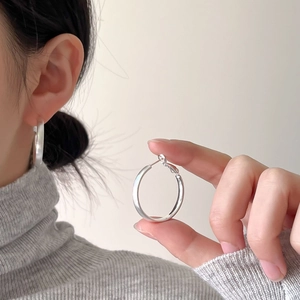 Minimalist brushed silver hoop earring shown on ear and held to highlight metallic texture