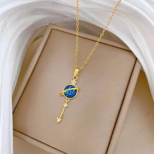 Macro shot of gold planet pendant with blue orb and crystal stars on silk background