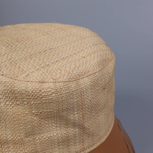 Dettaglio ravvicinato della trama in paglia di rafia naturale del cappello a secchiello