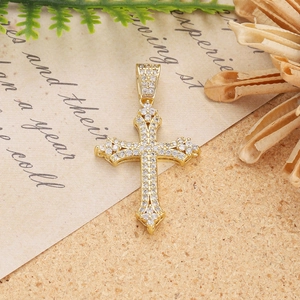 Detailed close-up of golden cross pendant with micro-set zircon on vintage paper background