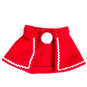 Detail of red Christmas pet cape with white pom-pom and wavy trim on soft fleece fabric
