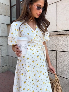 Detail of white floral wrap dress with puff sleeves and waist tie in casual street setting