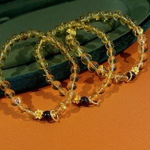 Detailed macro view of yellow citrine bead bracelets with golden flower charms and garnet accents