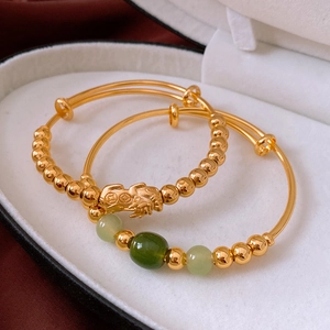 Detail of 18k gold plated Pixiu jade bracelets displayed in a white luxury gift box