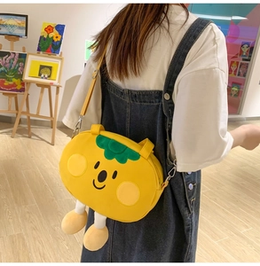 Cute yellow persimmon shaped canvas crossbody bag with creative plush legs on back of model