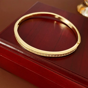 Macro view of gold geometric open cuff bracelet with zircon accents on a wood box