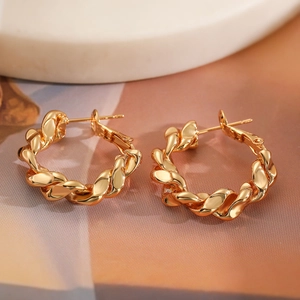 Vue macro de boucles d'oreilles torsadées dorées avec une finition métal polie