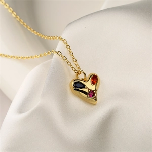 Close-up of golden heart pendant with colorful crystals on soft silk fabric