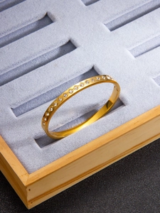 Macro detail of gold-plated titanium steel bangle with diamond-set rhombic pattern textures
