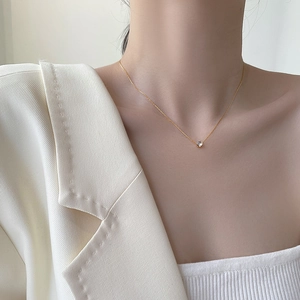 Elegant gold necklace featuring a minimalist round diamond pendant on a female model
