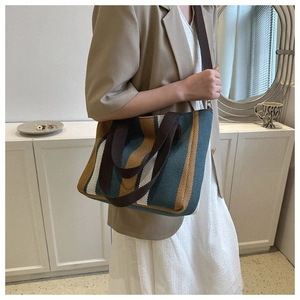 Detail of the green and yellow striped canvas tote bag with brown webbing shoulder strap