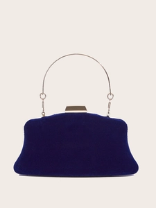 Close-up of dark blue velvet evening clutch featuring a gold circular handle and clasp