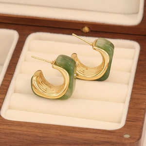 Boucles d'oreilles rétro en résine ambrée dorées en forme de C sur un écrin en bois