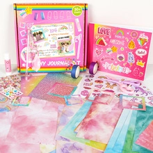 Flat lay of pink unicorn DIY journal set with stickers, tapes, scissors and glitter paper