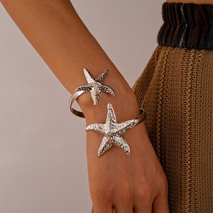Detail of silver starfish arm cuff with realistic texture on a warm knitted background