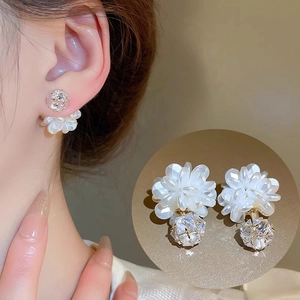 Detail of floral earrings featuring white petals and a zircon sphere on gold metal