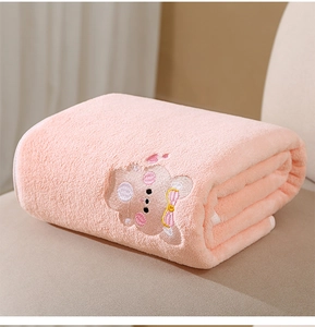 Close-up of pink coral fleece baby towel with detailed animal embroidery and soft texture